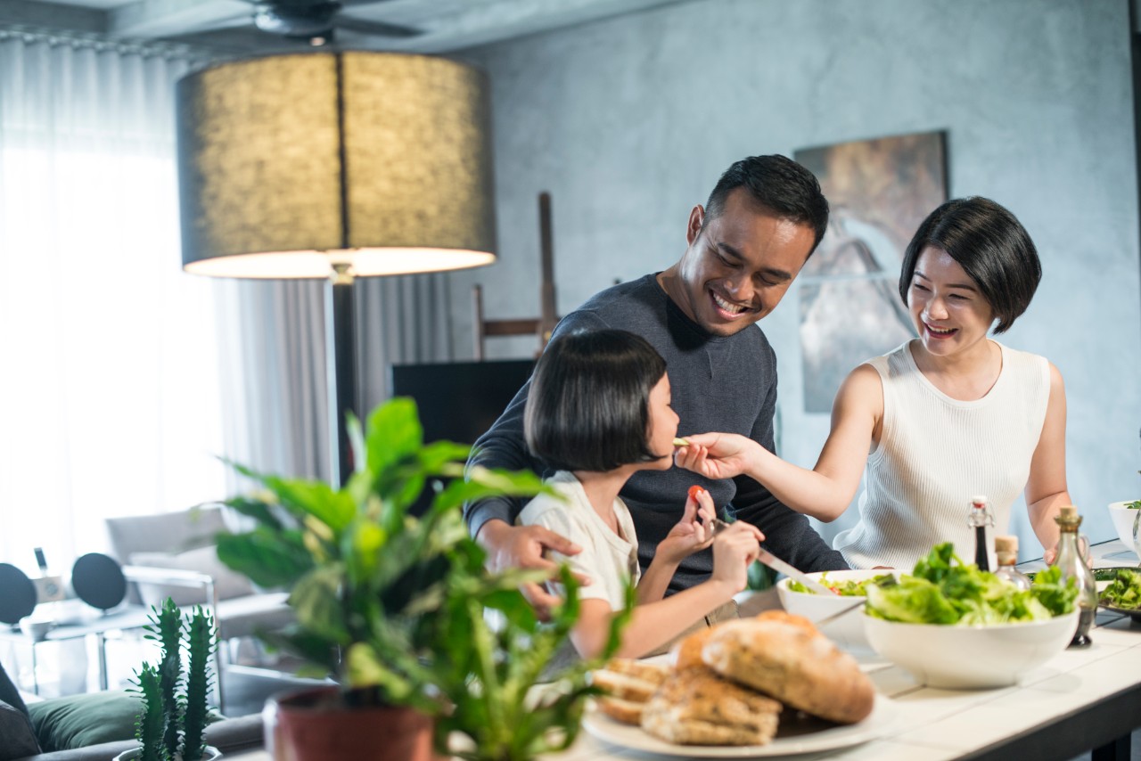 Happy young Asian family cooking together in the kitchen at home.